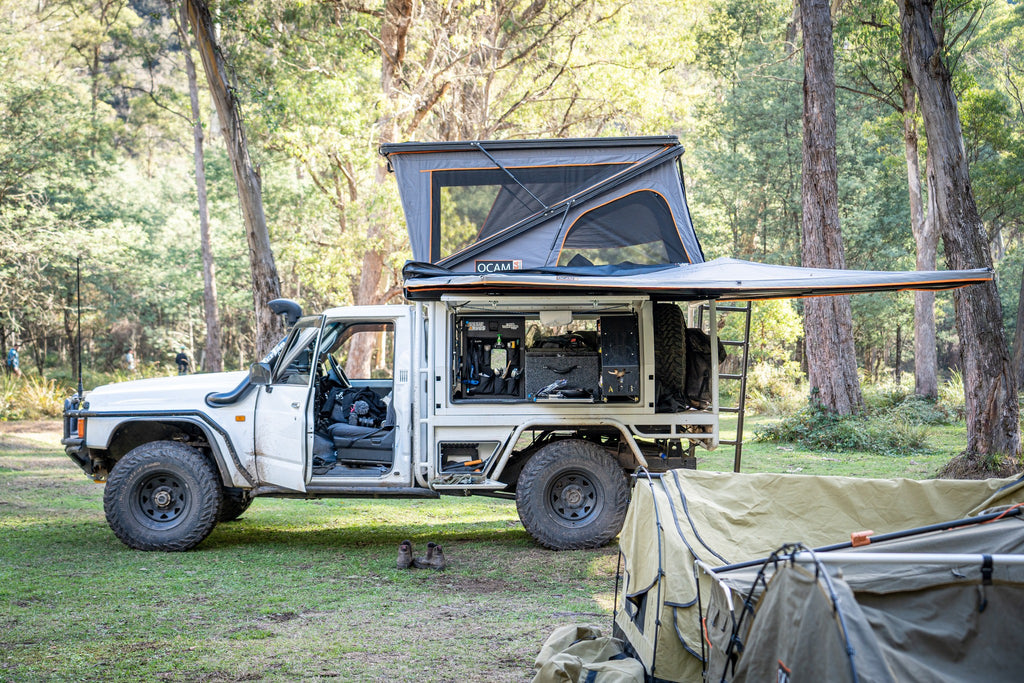 A white off-road vehicle equipped with a apboxes canopy and slide out pantry.