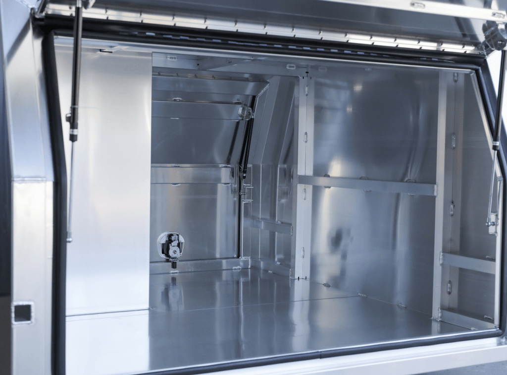 Interior perspective of apboxes lc79 1600mm 1-4 dog box canopy in alloy, with open doors and compartments.