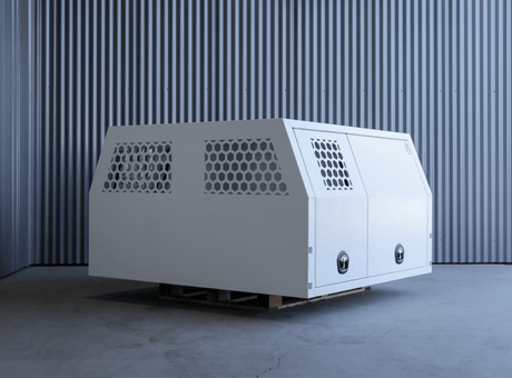 Apboxes LC79 1700mm full dog box canopy in white, positioned at an angle on a factory floor with doors closed.